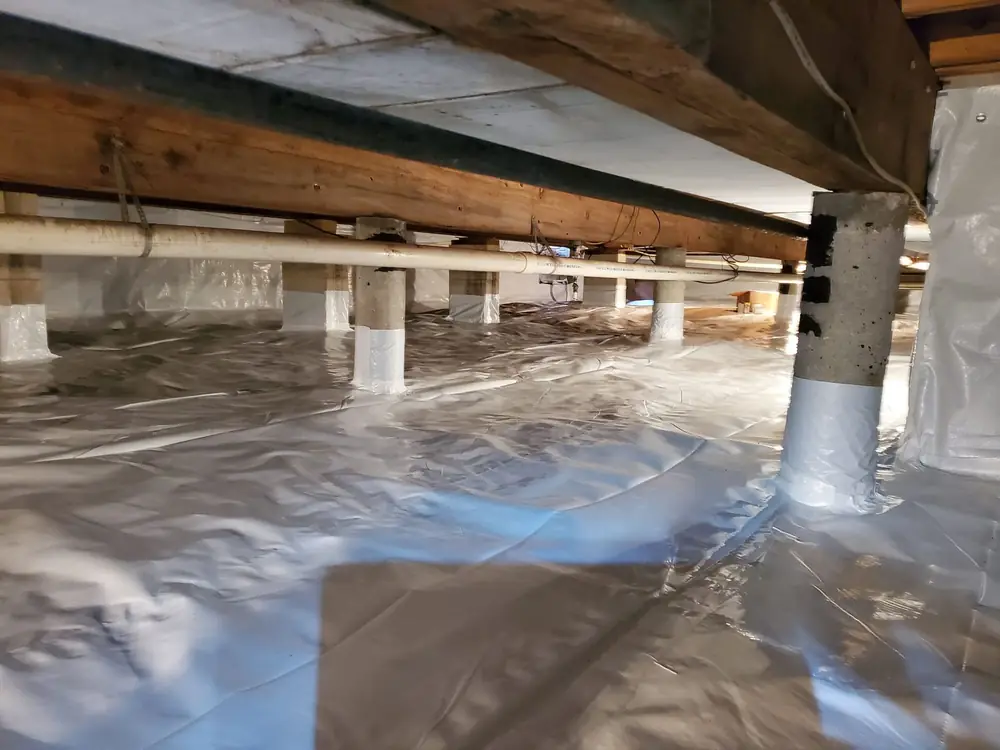 Crawlspace after encapsulation with a white vapor barrier over the floor and up the piers