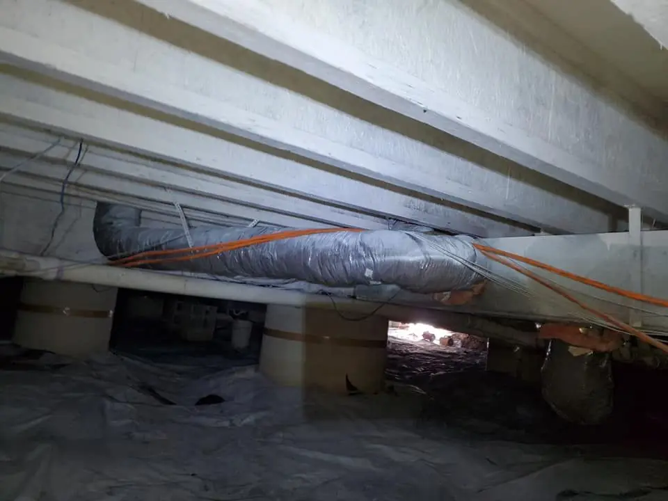 Crawlspace with ductwork above a new vapor barrier