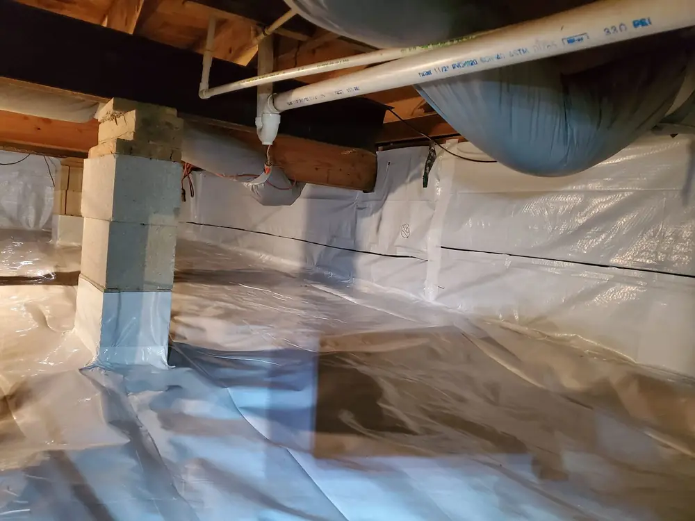 Crawlspace after encapsulation with a white vapor barrier over the floor and up the piers