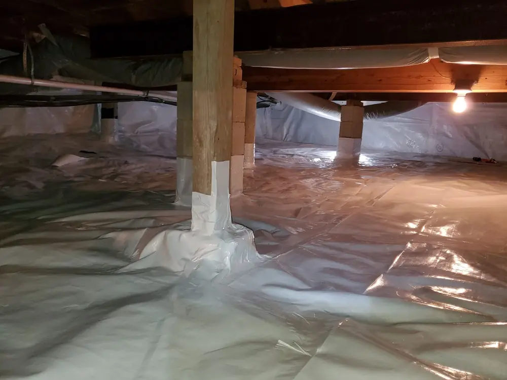Crawlspace after encapsulation with a white vapor barrier over the floor and up the piers
