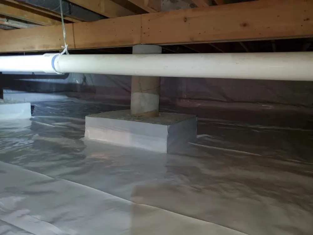 Crawlspace after encapsulation with a white vapor barrier over the floor and up the piers