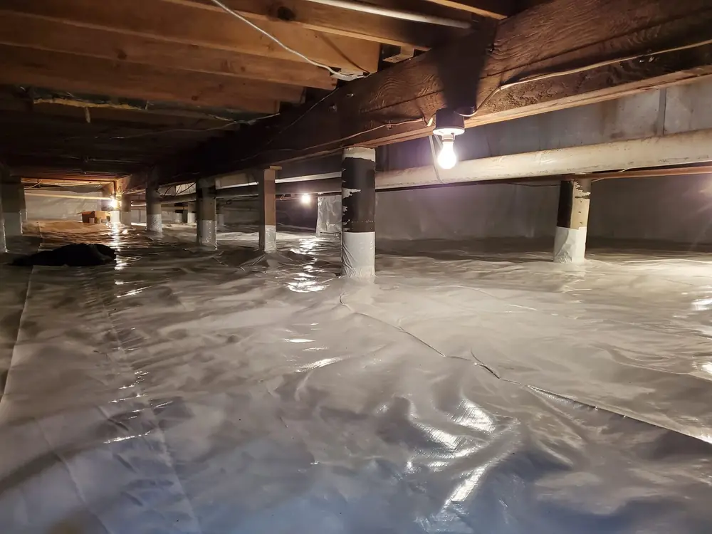 Crawlspace after encapsulation with a white vapor barrier over the floor and up the piers