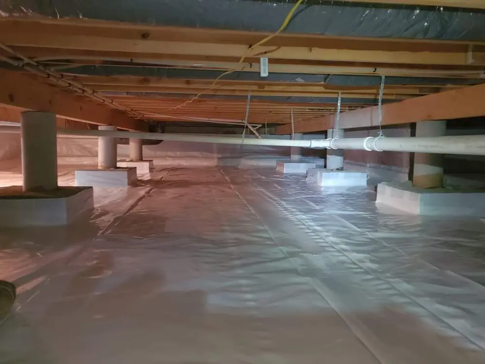Crawlspace after encapsulation with a white vapor barrier over the floor and up the piers